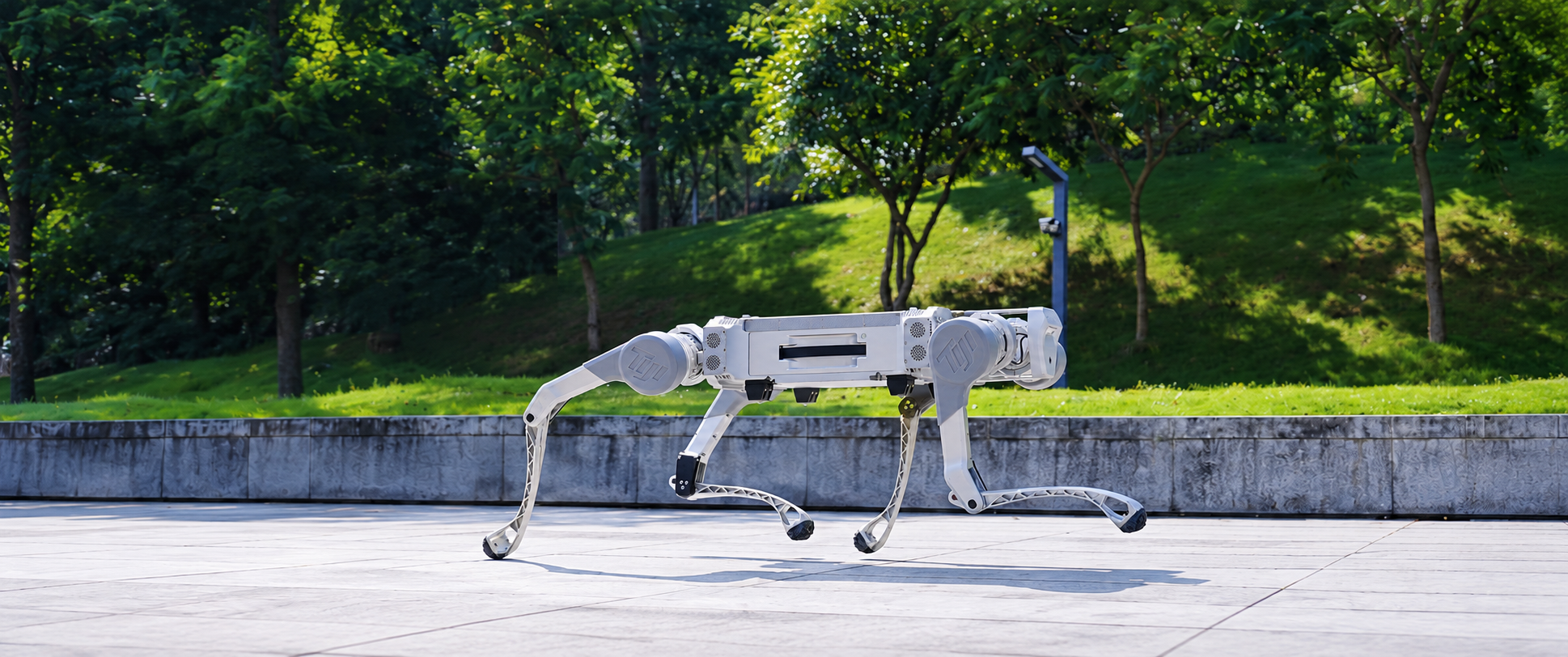银色蹄迹四足机器人在绿树环绕的户外道路上奔跑